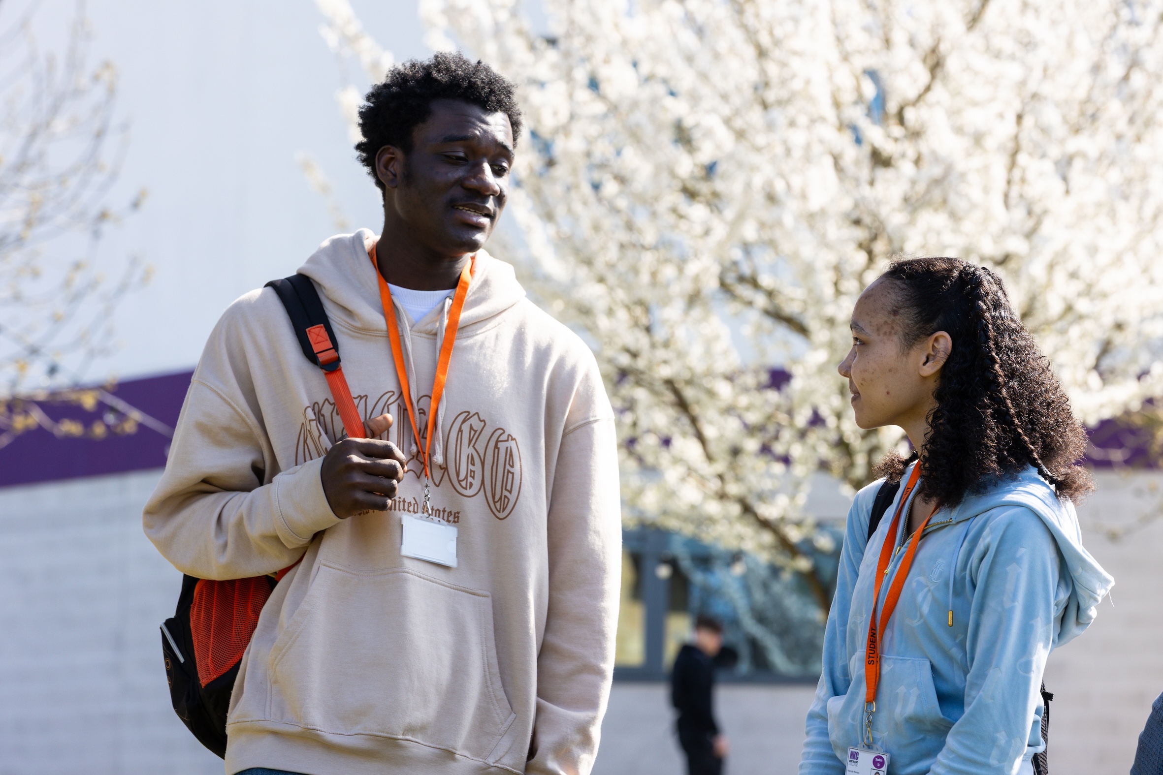 Two students outside standing looking at each other and talking