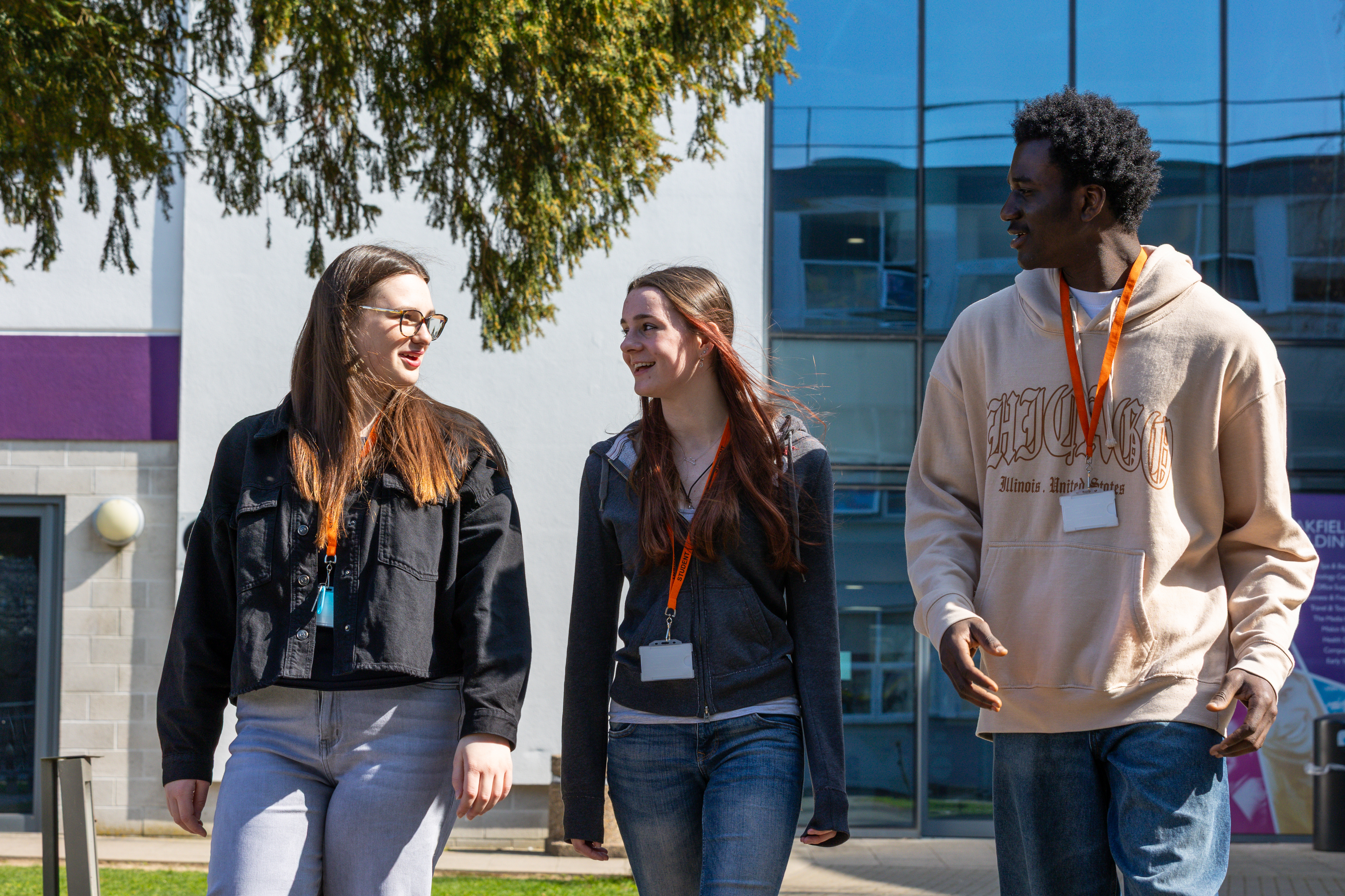 Three students walking in front of college building